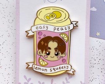Puede incluir: Un pin de esmalte dorado con un personaje de dibujos animados dentro de una lata rosa con el texto "easy peasy lemon squeezy".