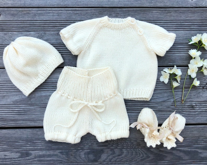 Puede incluir: Un conjunto de punto para beb&eacute; en color crema, que incluye un gorro, un jersey, unos pantalones cortos y unas botitas.