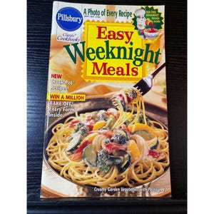 May include: A Pillsbury cookbook cover titled "Easy Weeknight Meals." The cover features a photo of pasta with vegetables. Text includes "New Crock-Pot Recipes!" and "Win a Million Bake-Off Entry Form Inside."