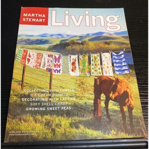 May include: A magazine cover for Martha Stewart Living. The cover features a scenic outdoor shot with dish towels hanging on a clothesline. The magazine's title is "Living". The cover also includes text about the magazine's content.