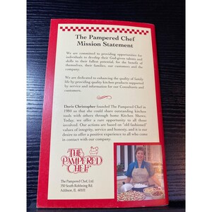 May include: A red and white brochure with "The Pampered Chef Mission Statement" printed on the front. The brochure includes text about the company's values and founder, Doris Christopher. A photo of a woman in an apron is also included.