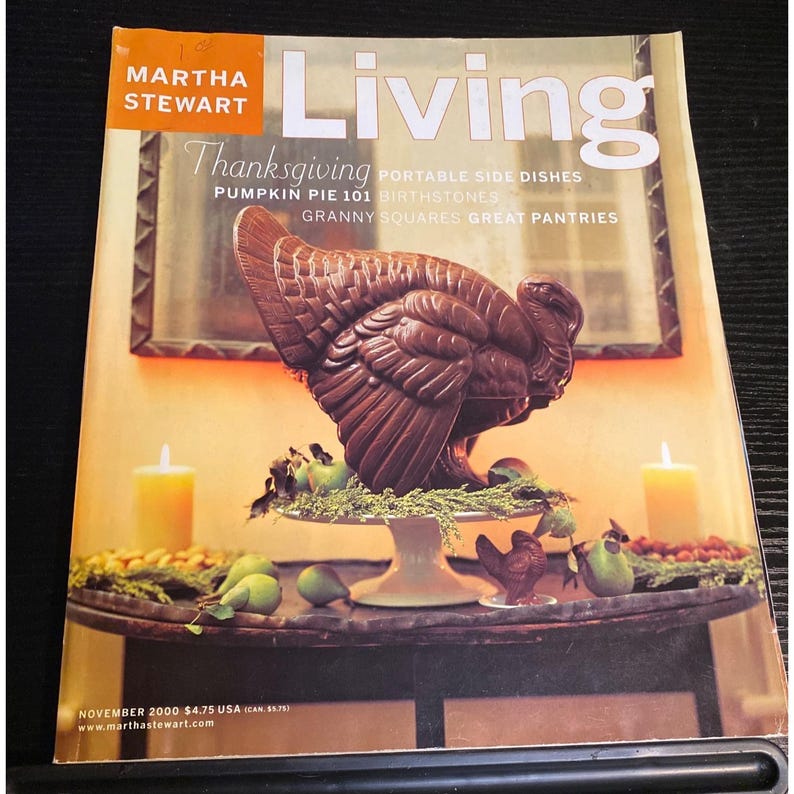 May include: A magazine cover featuring a Thanksgiving theme. The cover shows a chocolate turkey centerpiece on a cake stand, surrounded by pears, candles, and decorative elements. The magazine title is "Living" by Martha Stewart.