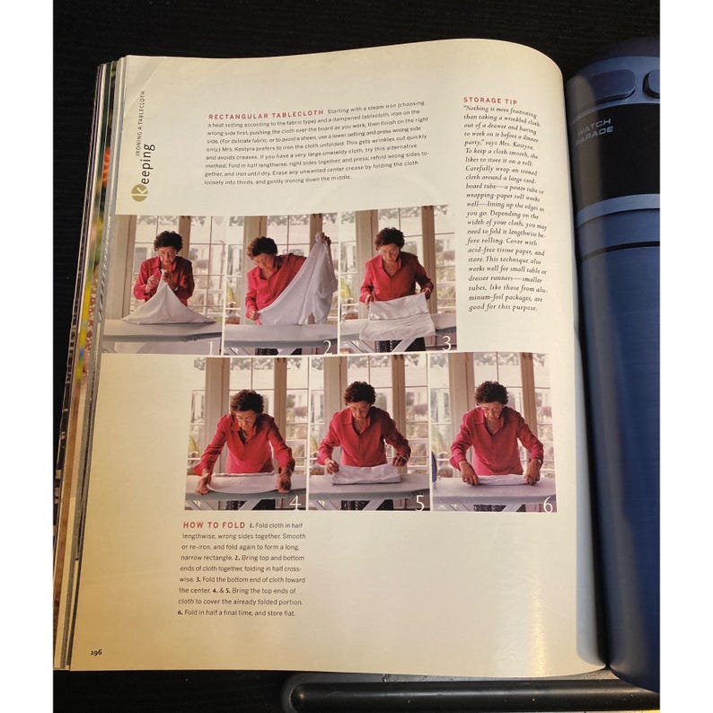 May include: A magazine page with step-by-step instructions on folding a rectangular tablecloth. The images show a person in a red shirt folding a white tablecloth on a table. Text includes "How to Fold" and "Rectangular Tablecloth."