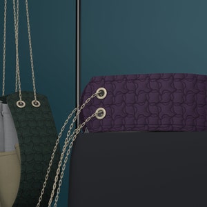 May include: A purple handbag with a chain strap and two silver metal rings. The bag has a textured, quilted design.
