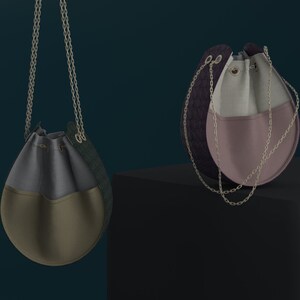 May include: Two round drawstring bags with chain straps. The bag on the left is green and brown, the bag on the right is purple and pink.