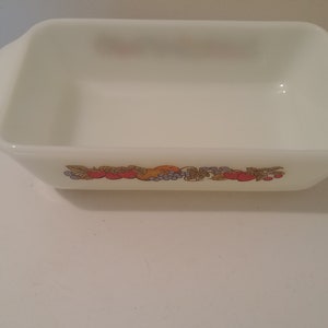 May include: White rectangular baking dish with a floral design featuring red, orange, and green fruits and leaves.
