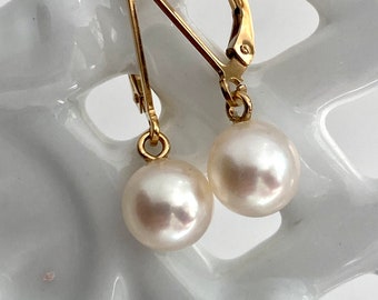 May include: A pair of gold earrings with white pearl drops. The earrings have a lever back closure.