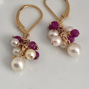 May include: Gold earrings with a cluster of white pearls and pink gemstones hanging from each earring.