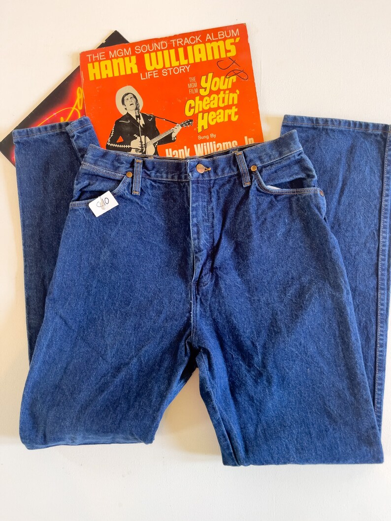 Puede incluir: Un par de pantalones vaqueros de mezclilla azul oscuro con cintura alta y pierna recta. Los vaqueros tienen un estilo cl&aacute;sico de cinco bolsillos y cierre de bot&oacute;n.