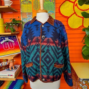 May include: A blue, green, red, and black patterned jacket with a brown corduroy collar and pockets. The jacket has a button closure and is made of a soft, fuzzy material.
