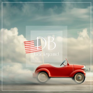 May include: A red toy car with a white steering wheel and black tires is driving down a road with a cloudy sky in the background. An American flag is attached to the car with a stick.