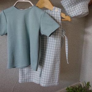 Peut inclure: Un t-shirt bleu clair avec une jupe et un chapeau assortis en vichy bleu clair et blanc.