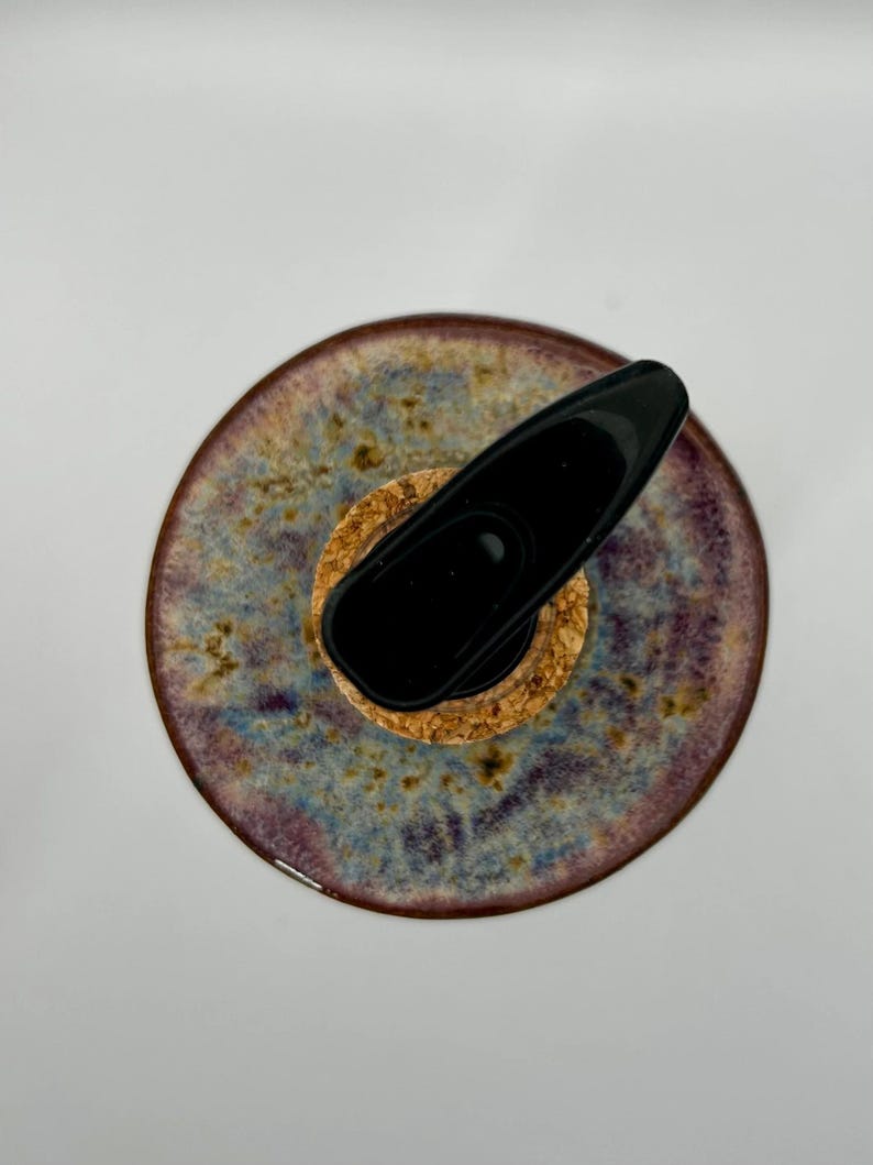 An overhead view of the stoneware soap dispenser, showing the mottled blue, purple, and brown glaze, cork, and black pump.