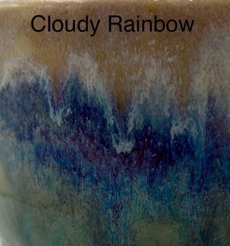 A close-up of a glaze sample labeled "Cloudy Rainbow," showing a top band of tan glaze dripping into mottled blue and purple below.