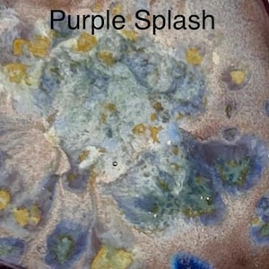 A close-up of a glaze sample labeled "Purple Splash," showing a textured surface with splotches of light blue, purple, and yellow.