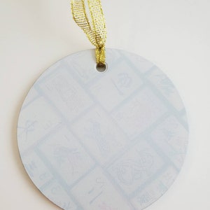 May include: A white round ornament with a gold ribbon attached. The ornament has a hole at the top for hanging and is covered in a light blue pattern.