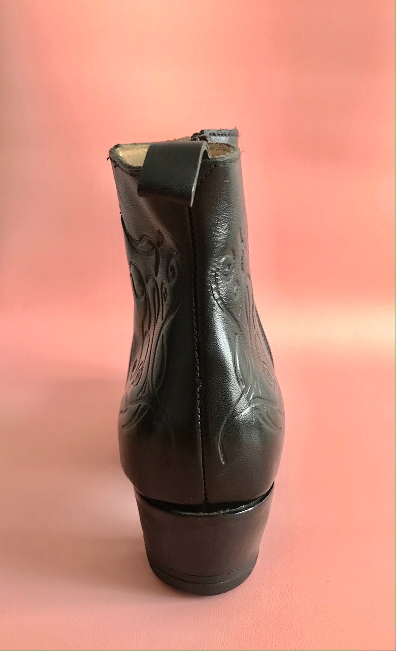 May include: Black leather ankle boots with a decorative floral pattern and a low block heel.
