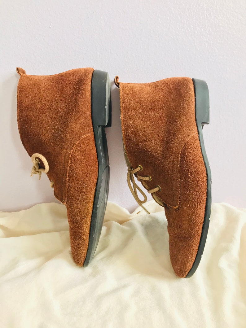 May include: A pair of brown suede ankle boots with laces. The boots have a rounded toe and a low heel.