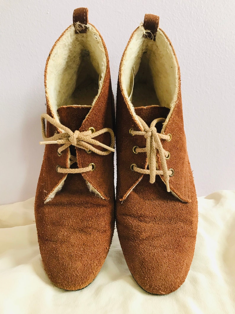 May include: A pair of brown suede ankle boots with laces and a faux fur lining.