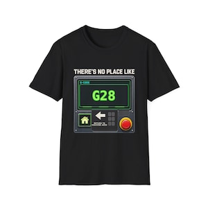 May include: A black short-sleeve t-shirt featuring a graphic of a machine control panel with a green digital display showing G28. Above the panel is the text THERE'S NO PLACE LIKE, and below the display is a home icon, an arrow, and a red button.