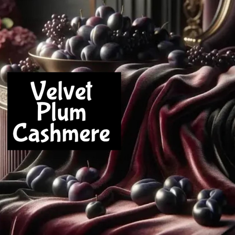 Pu&ograve; includere: Un primo piano di un tessuto di velluto rosso scuro con il testo "Velvet Plum Cashmere" in bianco. Il tessuto &egrave; drappeggiato su una ciotola di prugne e alcune prugne sono sparse sul tessuto.
