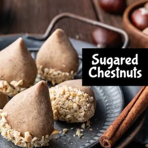 Puede incluir: Primer plano de castañas azucaradas, cubiertas de nueces picadas, en un plato gris con una rama de canela. El texto "Sugered Chestnuts" se muestra en texto negro sobre fondo blanco.