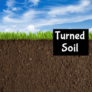 May include: A close-up of dark brown soil with green grass growing on top. The text "Turned Soil" is written in white on a black rectangle.