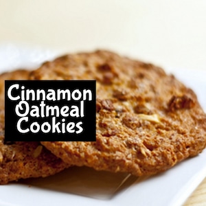 May include: Close-up of two cinnamon oatmeal cookies. The cookies are golden brown and have a slightly crispy texture. The text "Cinnamon Oatmeal Cookies" is displayed in white letters on a black background.