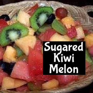 Op de afbeelding: Een kom fruitsalade met kiwi, meloen en rode bessen. De salade is gelabeld "Sugar Kiwi Melon".