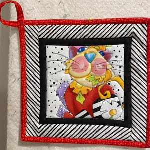 Peut inclure: Un dessous de plat coloré sur le thème du chat avec une bordure rayée noire et blanche et une bordure extérieure rouge. Le chat porte une tenue rouge, blanche et noire et a une feuille verte dans sa bouche.