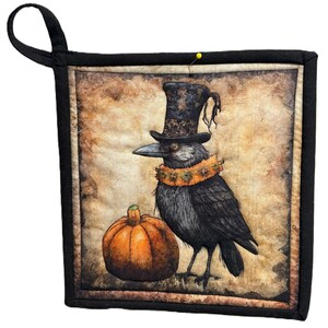 May include: Square black pot holder with a Halloween theme. The image features a black crow wearing a top hat and a decorative collar, standing next to an orange pumpkin. The background has a vintage, aged paper appearance.