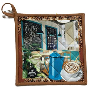 Peut inclure: Un dessous de plat carré et matelassé avec une bordure marron et une boucle de suspension. Le centre représente une scène de café avec une cafetière bleue, un latte et un menu sur tableau noir. La bordure est ornée de grains de café.