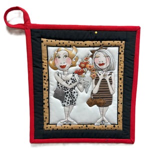 May include: Square quilted pot holder with a red border and hanging loop. The center features an illustration of two women holding flowers. One woman wears a black and white patterned dress, the other a brown striped dress. The background has a black and tan spotted border.