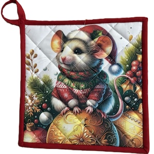 May include: A quilted Christmas potholder with a red border and hanging loop. The design features a mouse wearing a Santa hat and a red and green sweater, sitting on a decorative ornament. Festive holiday decor.