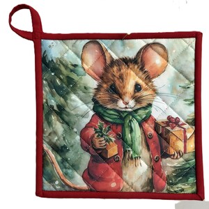 May include: Quilted Christmas potholder with a watercolour illustration of a mouse in a red coat and green scarf, holding gifts. The potholder has a red border and hanging loop, with a diamond pattern.