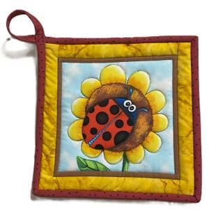 Pode incluir: Uma joaninha vermelha e preta com manchas brancas está sentada em um girassol amarelo com um centro marrom. O girassol está em um fundo azul e branco com uma folha verde. A imagem é emoldurada com uma borda amarela e marrom e uma borda vermelha com bolinhas brancas.