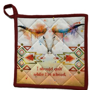 Può includere: Presina quadrata trapuntata con bordo bordeaux e anello per appenderla. Il centro presenta un disegno ad acquerello di un teschio di longhorn con schizzi di vernice colorati. Il testo: "I should quit while I'm a head."