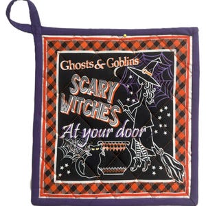 Könnte beinhalten: Quadratischer, gesteppter Topflappen mit einer lila Aufhängeschlaufe. In der Mitte steht der Text "Ghosts & Goblins SCARY WITCHES At your door" mit einer Hexe auf einem Besen, einer schwarzen Katze und einem Kessel. Der Rand ist orange-schwarz kariert.