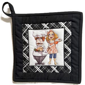 Può includere: Presina trapuntata nera con bordo a quadri bianchi e neri. Il centro presenta un'illustrazione colorata di uno chef e di una donna che tiene una torta. Lo chef tiene in mano un tacchino arrosto. La donna indossa un grembiule.
