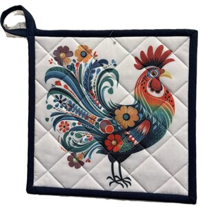 May include: A square, quilted pot holder with a colorful rooster design. The rooster features red, orange, blue, and green details, with floral accents. The pot holder has a white background with a diamond pattern and a navy blue border and hanging loop.