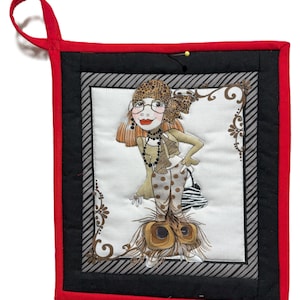 May include: A quilted potholder with a red border and a black and gray striped inner border. The center features a whimsical illustration of a woman in a leopard print hat and polka dot pants, with a peacock feather skirt.