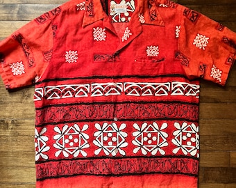 Op de afbeelding: Een rood-wit, kort mouwig overhemd met knopen en een geometrisch patroon. Het shirt heeft een label met de tekst "KEOKI" en "HAWAIIAN SHIRTS".