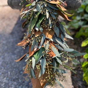 May include: A green and brown eucalyptus and magnolia leaf garland. The garland is made of fresh leaves and is perfect for adding a touch of nature to your home.