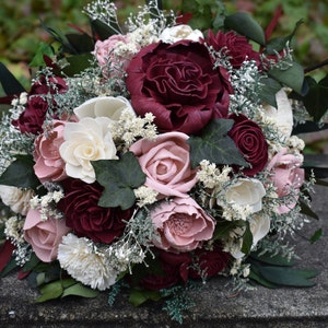 May include: A bouquet of burgundy and blush sola wood flowers with white sola wood flowers and greenery.