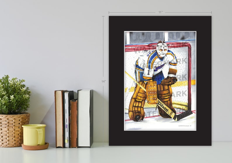 May include: A watercolor painting of a hockey goalie in a blue and gold uniform, wearing a mask and holding a hockey stick. The goalie is in a defensive position, with his pads and glove extended. The painting is framed in black and measures 11 inches by 14 inches.