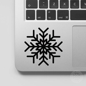 May include: Black snowflake sticker on a silver laptop.