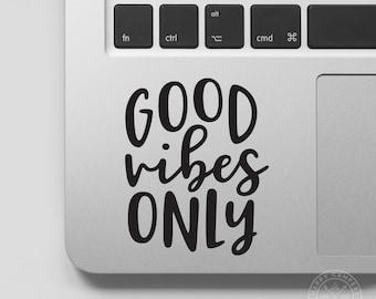 May include: A laptop with a black and white sticker that says "GOOD vibes ONLY" on the trackpad.