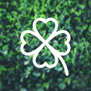 May include: A white outline of a four-leaf clover on a blurred green background.