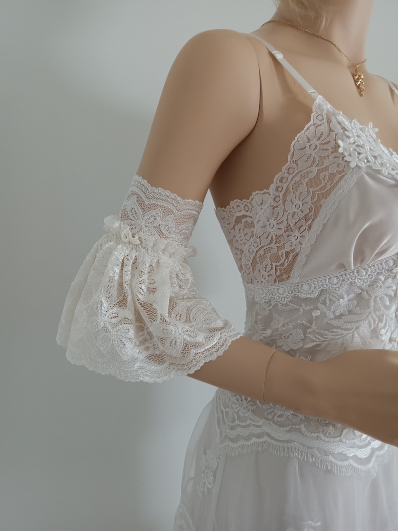 May include: White lace lingerie with a frilled sleeve. The lingerie features a delicate floral pattern and a satin bodice.