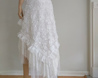 May include: White lace skirt with a ruffled hem and a 3D floral design. The skirt is layered with tulle and has a high waist.